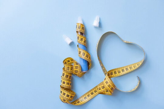 Dangers of unhealthy weight loss. Medical injection pen wrapped with a yellow measuring tape forming a heart shape, warning against severe side effects and obsession with thinness.