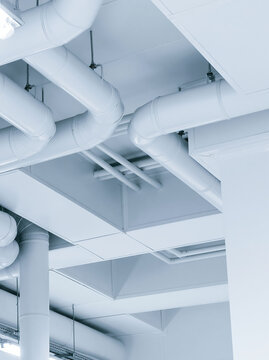 Industrial ceiling pipes white ventilation ducts in contemporary manufacturing plant interior