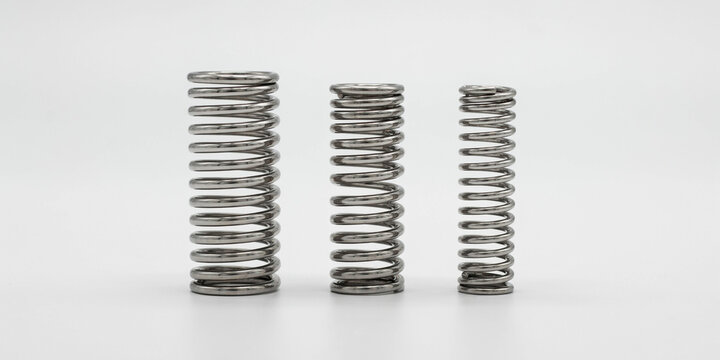 Three industrial steel compression springs of different sizes on a white background