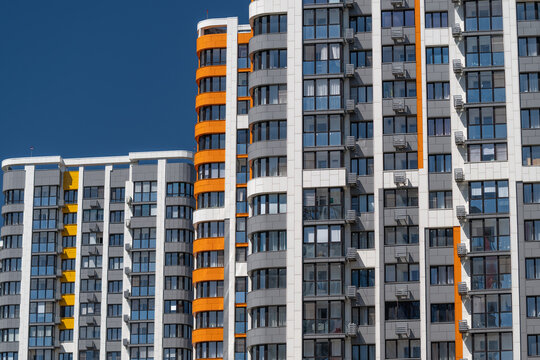 Modern buildings showcase striking orange accents against a clear blue sky in an urban landscape