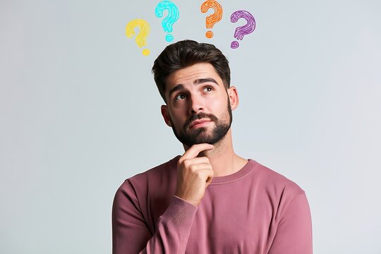 Thoughtful young man with a beard looking up at colorful handdrawn question marks floating above his head, expressing curiosity and confusion