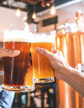 Friends clinking fresh craft beer glasses in a warm brewery, celebrating togetherness and festive joy with refreshing ale in hand. Ideal for pub menus and nightlife promotions.