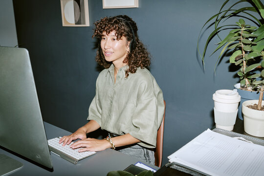 Young adult Biracial woman working in call center typing on computer. Image suitable for customer support, and telemarketing