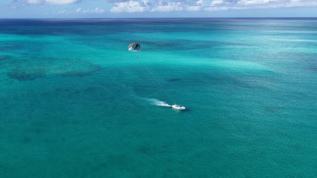 Parasailing In Providenciales Turks And Caicos United Kingdom. Thrilling Adventure With Speedboat Paragliding In Turquoise Ocean. Landmark Coast. Bay Water Landscape. Providenciales Turks and Caicos.