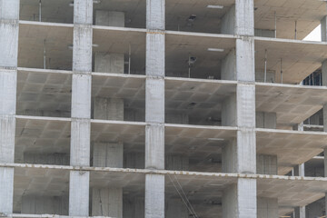 Fototapeta premium New building structure is under construction in a busy city, showing raw concrete and empty floors in the early afternoon