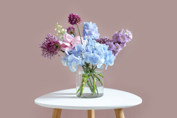 Obraz premium Bouquet of beautiful flowers in vase on white table near beige wall indoors, closeup
