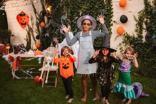 Four young girls celebrating Halloween in spooky costumes outside in a decorated garden