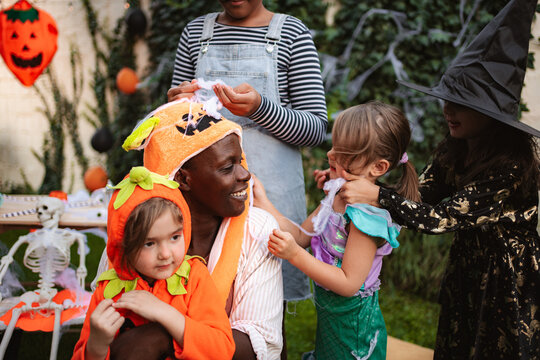 Children and adult enjoying Halloween festivities in costumes and spooky decorations outdoors