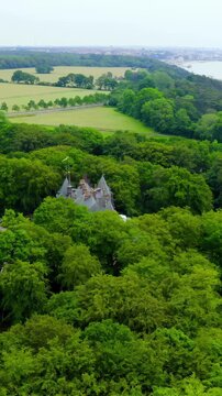 Vertical video. Sweden. Sofiero Palace, a Dutch Renaissance summer residence with steep slate roofs and pointed turrets, set amid dense green woodland above the Oresund Strait, Drone footage., Point 