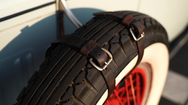 A spare spoked wheel on a vintage car mounted on the fender