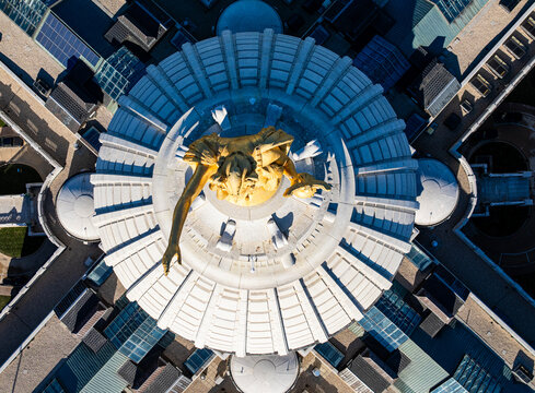 Overhead top-down aerial drone view of the golden Wisconsin statue atop the circular dome of the Wisconsin State Capitol building in Madison. Geometric architectural abstract photography.