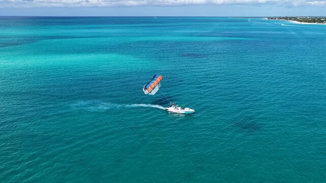 Parasailing In Providenciales Turks And Caicos United Kingdom. Thrilling Adventure With Speedboat Paragliding In Turquoise Ocean. Summer Backgrounds. Bay Water Landscape.