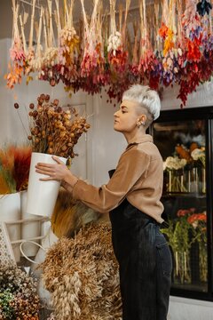 Young female florist holding fresh flowers in a colorful flower shop