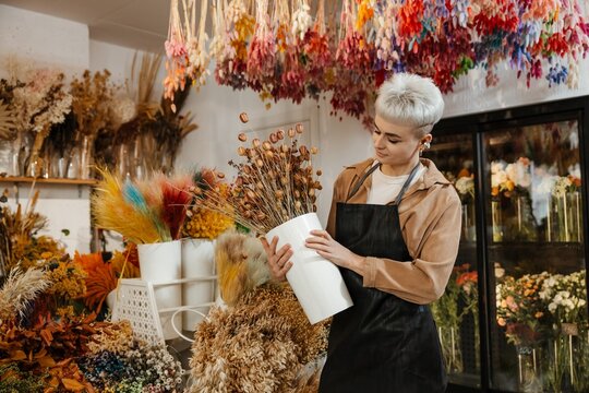 Young female florist holding fresh flowers in a colorful flower shop