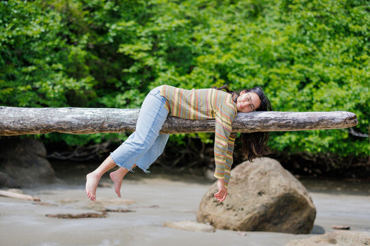 Girl laying on log in summer sun, Haida gwaii