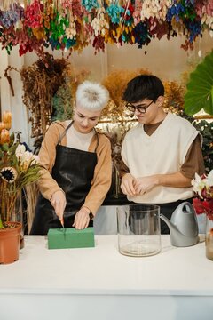 Two young florists arranging fresh flowers in a colorful flower shop