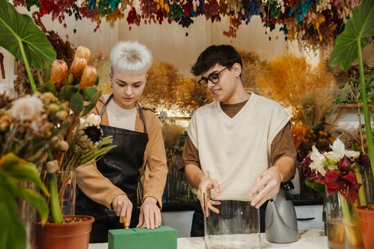 Two young florists arranging fresh flowers in a colorful flower shop