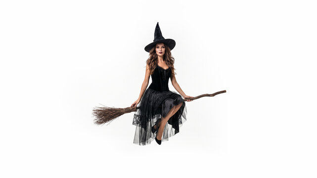 Beauriful model wearing adult witch costume flying on a broom isolated against a white background for Halloween with copy space