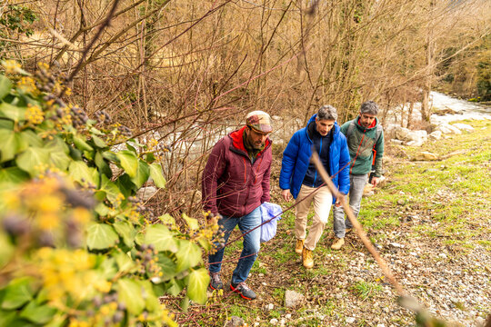 Friends collect plastic waste beside a forest river