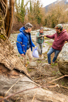 Friends collect plastic waste and fist bump by river