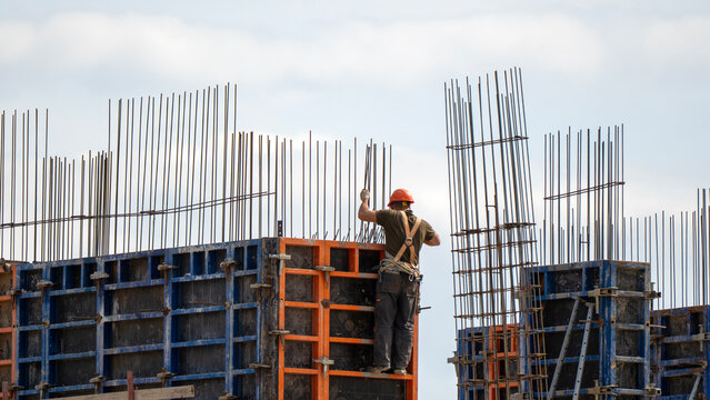 Worker stands atop steel frame, adjusting rebar with care