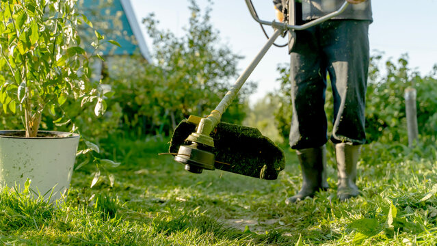 Person trims grass with a cordless edger