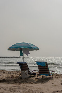 Vertical beach chairs with umbrella bag and flip flops by sea