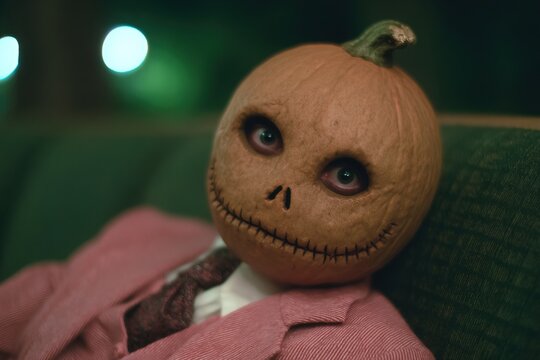 Creepy pumpkin-headed doll in pink Halloween costume