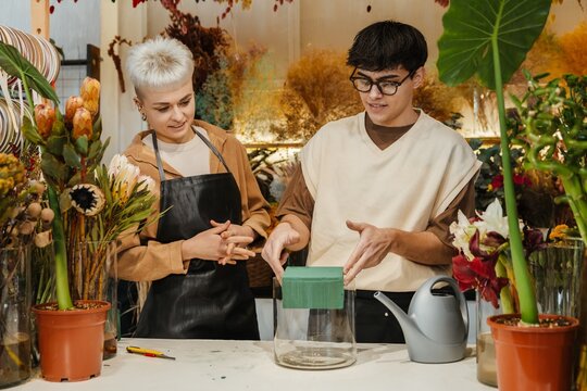 Two young florists arranging fresh flowers in a colorful flower shop