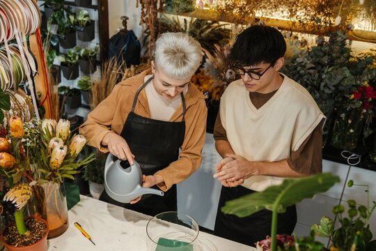 Two young florists watering plants in a colorful flower shop