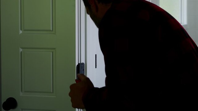 Homeowner applying aerosol silicone lubricant spray grease oil to interior door hinges wiping away residue during routine home maintenance repair work