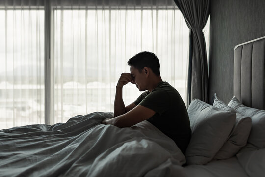 Stressed Man Sitting in Bed Feeling Overwhelmed by Anxiety, Worry and Life Problems
