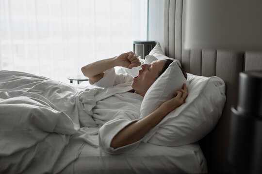 Sleepy Woman Yawning While Waking Up in Bed in the Morning
