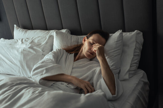 Tired Woman Rubbing Her Eyes While Resting in Bed After Poor Sleep
