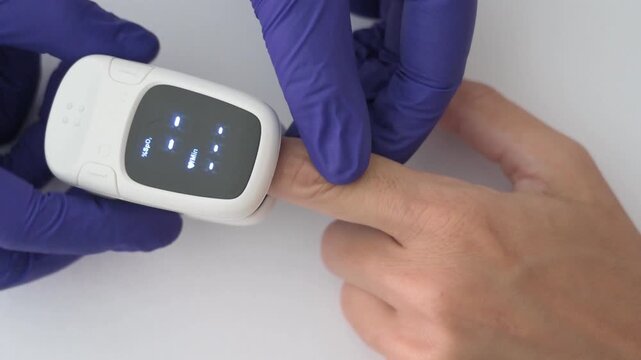Healthcare worker placing pulse oximeter on finger to measure blood oxygen