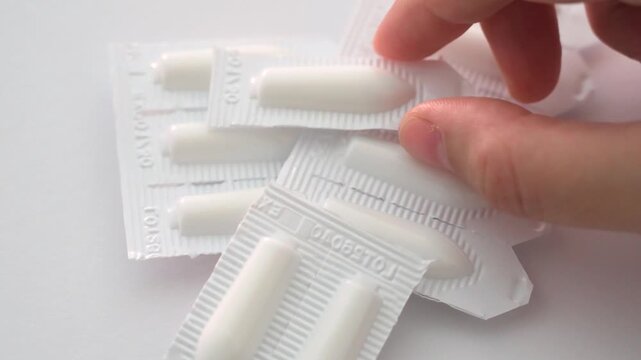 Female hand grabbing single unbranded medicine suppository for treatment dose