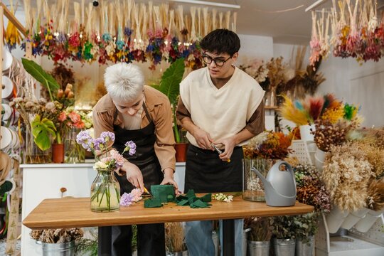 Two young florists arranging fresh flowers in a colorful flower shop