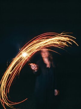 Woman create cinematic sparkler light trails at night