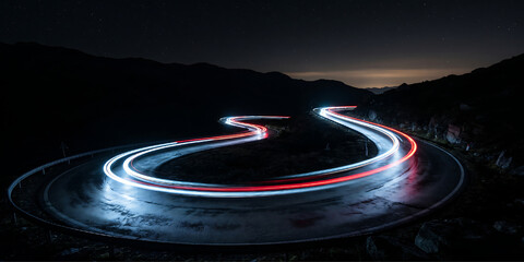 Winding mountain road illuminated by red and white light trails at night under a starry sky. © Tafrin