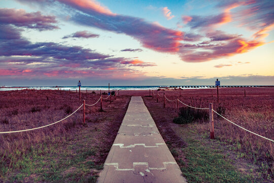  Paseo mar&iacute;timo de madera, campo de lavanda, espectacular atardecer, cielo colorido. Camino de madera a trav&eacute;s del campo de lavanda p&uacute;rpura bajo un v&iacute;vido cielo al atardecer. Concepto de naturaleza