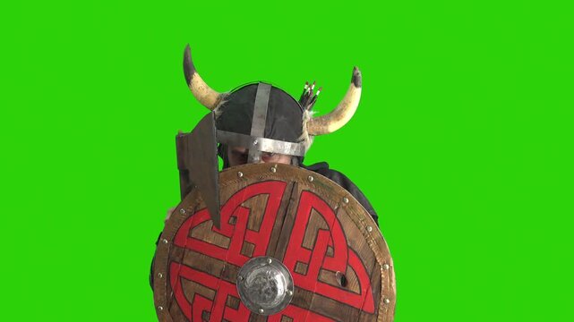 Bearded viking warrior in horned helmet with axe rising from behind a round wooden shield, isolated on a green screen background for chroma key compositing