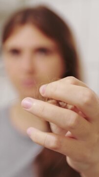 Close-up of a woman holding a clump of fallen hair in front of her face, illustrating hair loss and health problems. Woman holding a clump of falling hair showing hair loss and shedding problems