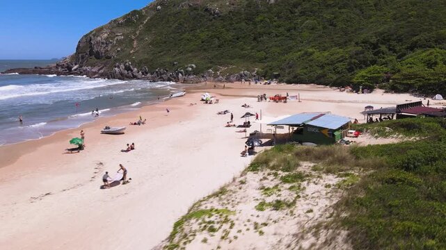 Drone Low Angle View of Lagoinha do Leste Beach in Florianopolis with Rustic Brazil Bar on Sand, Tourists Relaxing by Rocky Coast and Ocean Waves, Summer Tropical Forest Destination Travel Footage
