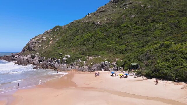 Drone Aerial View of Hikers on Lagoinha do Leste Beach near Steep Rocky Mountain in Florianopolis Brazil, Wild Coastline and Atlantic Forest Trekking Trail, Summer Adventure Travel Footage
