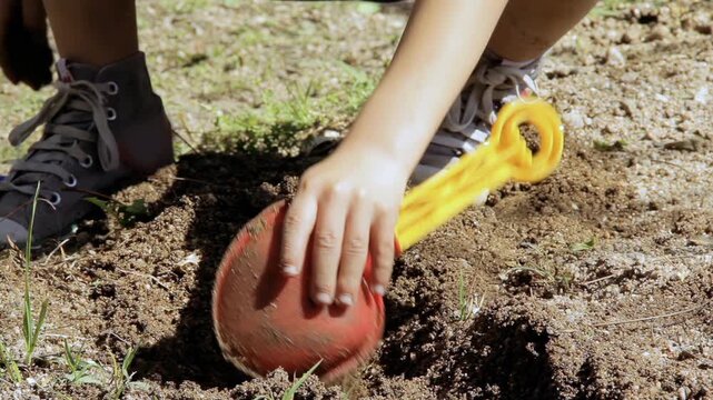Close Up of Child Playing with Dirt and Plastic Toy Shovel Outdoors - 4K