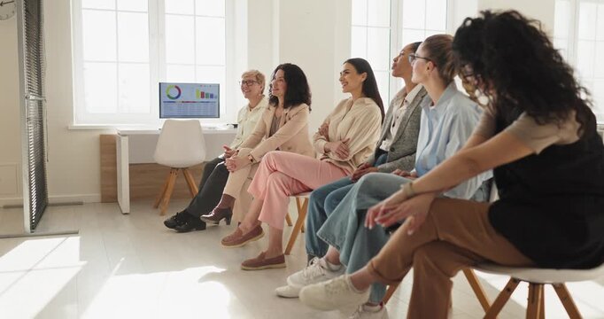 Business women audience listening during coaching seminar. A group attends training in a bright office, with charts on screen guiding strategy and presentation. Teamwork and learning concept.