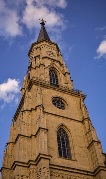 Ghotic church tower against blue sky with clouds