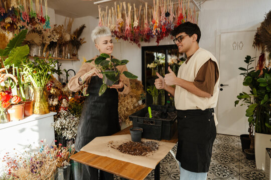 Two young florists holding plant in a colorful flower shop