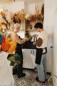 Two young florists washing flowers in a colorful flower shop