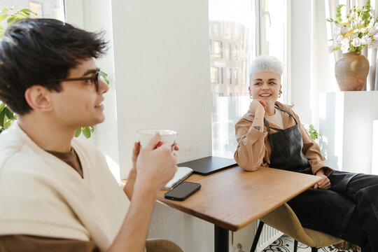 Two young florists drinking coffee in a colorful flower shop